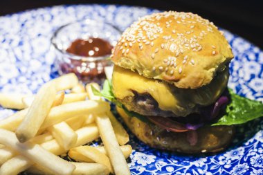Tavuk burger, patates kızartması ve sos restaura 'da mavi tabakta.