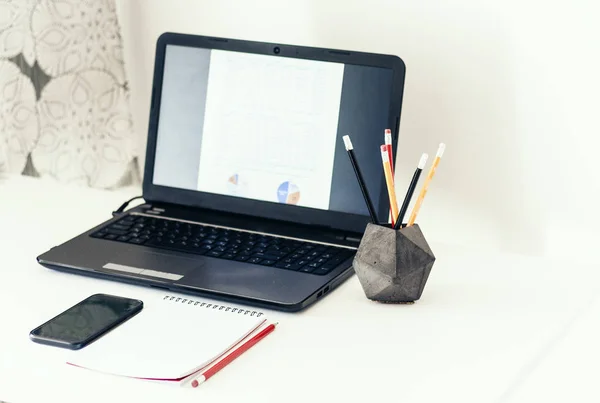 Laptop, smartphone, notebook en potloden in betonnen houder op w — Stockfoto