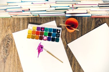Suluboya boya, iyi kullanılmış fırçalar ve tahta üzerinde kağıt.