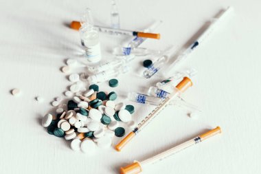 Beyaz b üzerinde ampul ve şırınga bulunan ilaç hapları veya kapsüller.