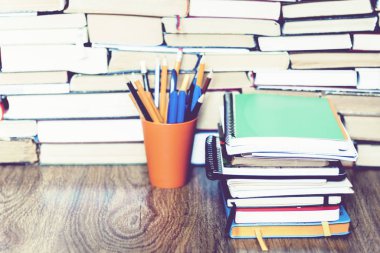 Renkli kalemler kitap eğitimi üzerine defter yığınıyla birlikte tutulur