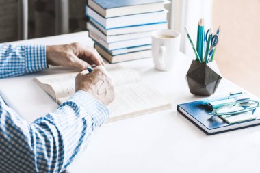 Mavi gömlekli bir adam modern moda işyeri üzerine kitap okuyor.