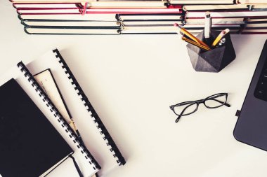 Kitap yığını, defter, dizüstü bilgisayar, ofis arka planında gözlük...