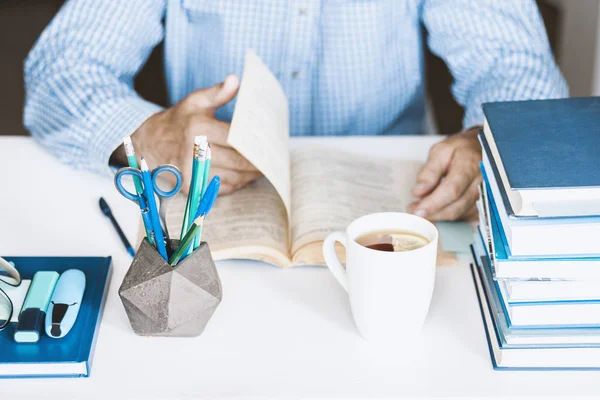 Hombre de camisa azul libro de lectura en un lugar de trabajo moderno y elegante con — Foto de Stock