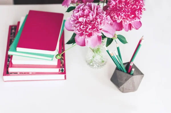 Buquê de peônias rosa, uma pilha de livros, lápis e um noteboo — Fotografia de Stock