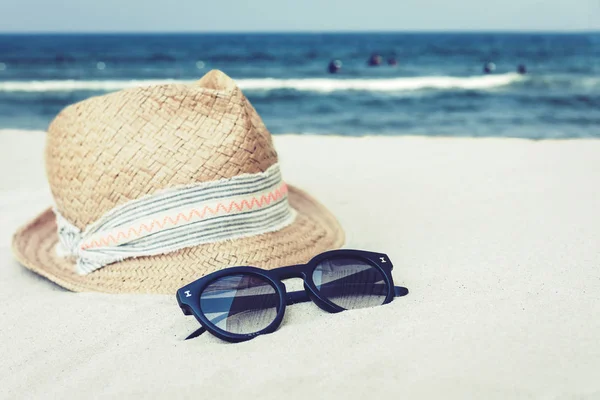 Vintage wicker straw hat and black sun glasses on a tropical bea