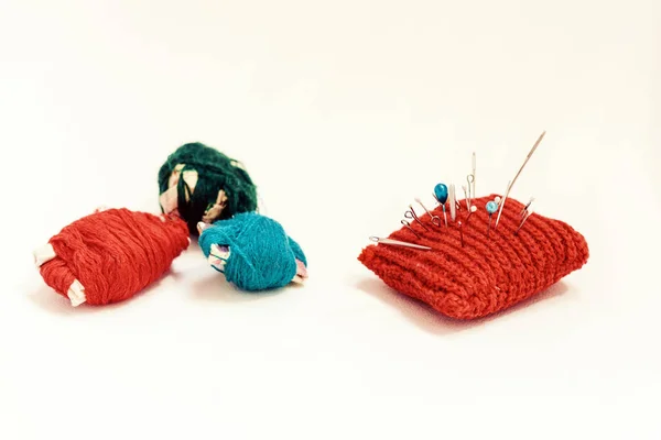 Tapis à aiguille tricoté rouge pour la couture et les bobines de fil coloré sur wh — Photo