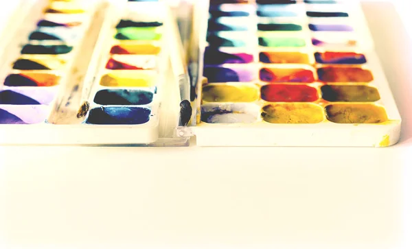 Watercolor paint and brushes well used on white wooden table wit — Stock Photo, Image