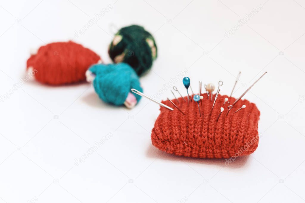 Red knitted needle pad for sewing and colored thread coils on wh