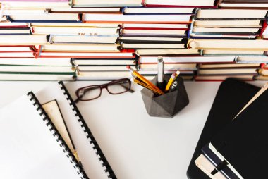 Kitap yığını, ders kitabı, laptop, ofis çantasındaki gözlükler.