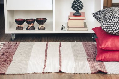 Konforlu ev dekorasyonu, kitap yığınlarıyla dolu beyaz komodin.