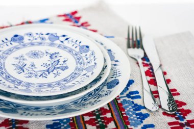 Akşam yemeği için masa: beyaz ve mavi tabaklar, bir çatal, bir bıçak.