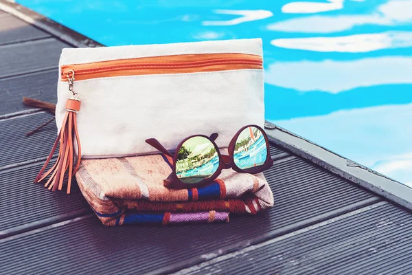 sun glasses, cosmetic bag, cover-up beachwear wrap near swimming