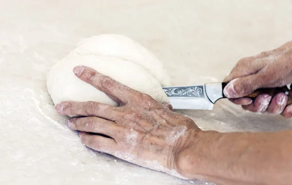 Mani femminili con un coltello tagliare la pasta sul tavolo in kitc — Foto Stock