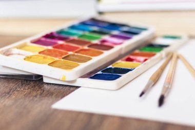 Suluboya boya, iyi kullanılmış fırçalar ve tahta üzerinde kağıt.