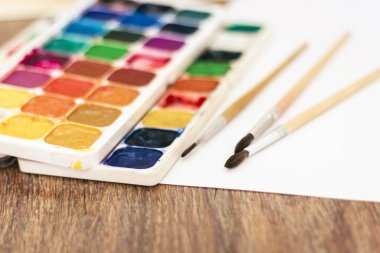 Suluboya boya, iyi kullanılmış fırçalar ve tahta üzerinde kağıt.