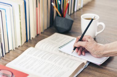Kitap yığını eğitim geçmişi, kadın eli notlar alıyor. 