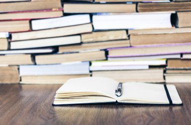 Eski kitap yığını, aç defter ve kalem. Eğitim kavramı geri döndü