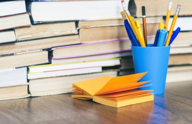 Mavi plastik tutacaklı renkli kalemler ve turuncu kağıtlar.