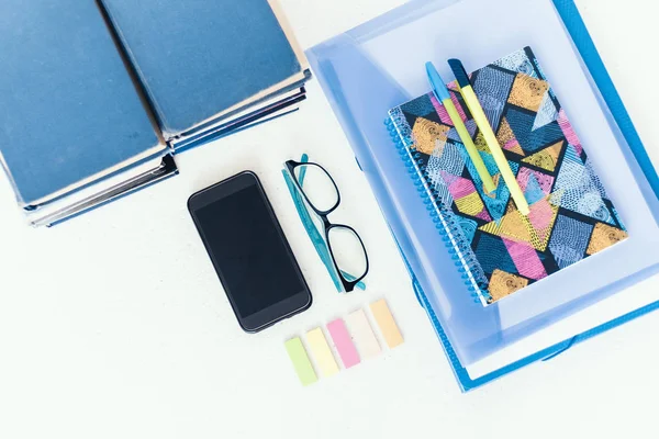 Libros azules de fondo, smartphone, notebook, gafas y bolígrafos en — Foto de Stock