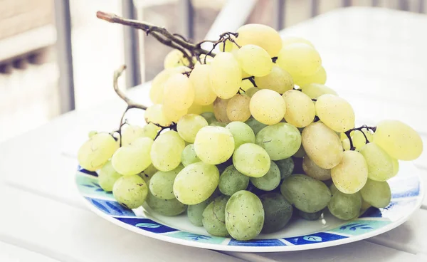 Bunch of green grapes on white plastic table — ストック写真