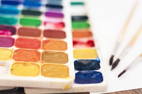 Akvarelová barva, dobře použité štětce a list papíru na dřevě — Stock fotografie