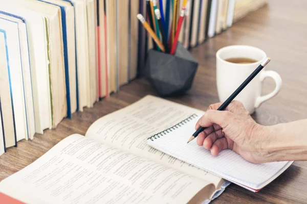 Pila de libros educación fondo, mano femenina hace notas en — Foto de Stock