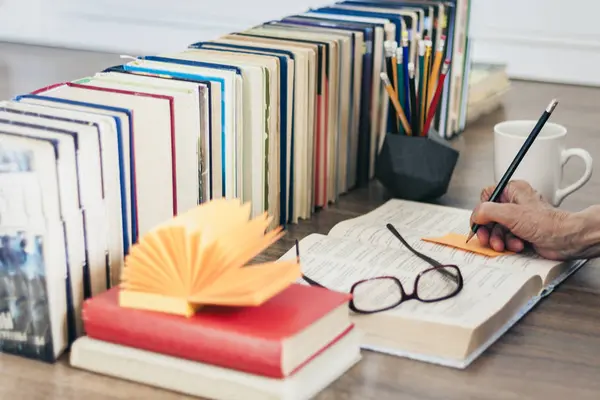 Pila de libros educación fondo, mano femenina hace notas nea — Foto de Stock