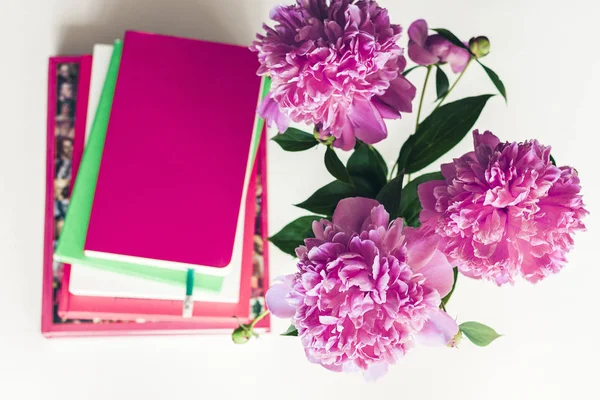 Buquê de peônias rosa, uma pilha de livros, lápis e um noteboo — Fotografia de Stock