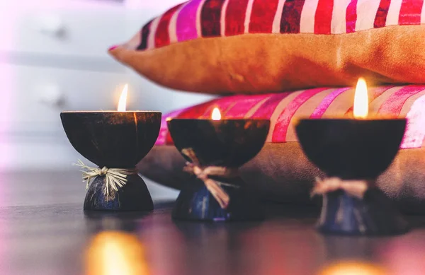 Queimando velas de aroma de spa em casca de coco e travesseiros de borgonha — Fotografia de Stock