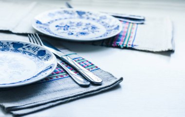 Akşam yemeği için sofra: beyaz tabak, çatal, bıçak.