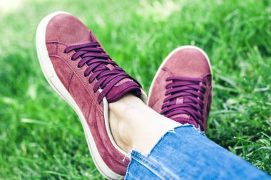 Spor ayakkabılı genç kadın bacakları, pembe süet ayakkabılar, oturuyor. 