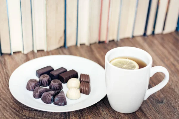 Chocolate candies on white plate  and cup of tea with lemon with — Stock Photo, Image