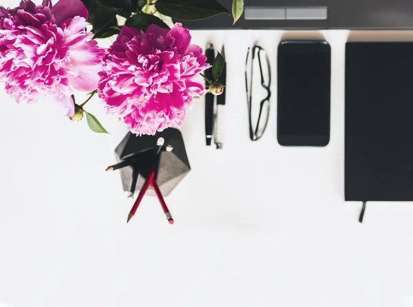 Buquê de peônias rosa, laptop, smartphone, canetas, óculos e um — Fotografia de Stock