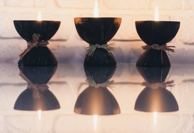 Cam beyaz bir masa üzerinde hindistan cevizi kabuğunda yanan spa aromalı mumlar.