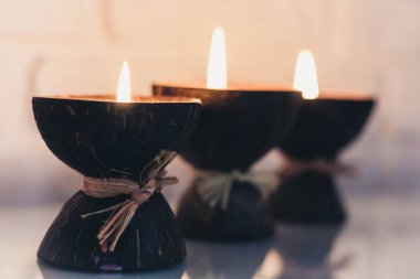 Cam beyaz bir masa üzerinde hindistan cevizi kabuğunda yanan spa aromalı mumlar.