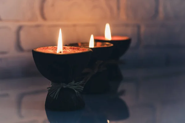 Velas ardientes del aroma del balneario en cáscara de coco en una tabla blanca de cristal — Foto de Stock