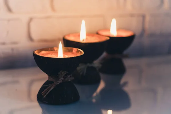 Queimando velas de aroma de spa em casca de coco em uma mesa branca de vidro — Fotografia de Stock