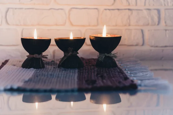 Velas ardientes de aroma spa en cáscara de coco en un multicol de punto — Foto de Stock