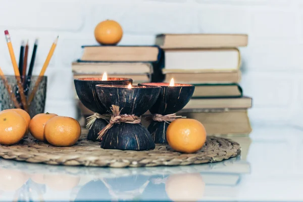 Hindistan cevizi kabuğunda yanan spa aromalı mumlar, hasır üzerinde mandalinalar