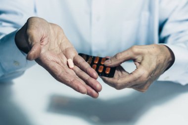Yaşlı kadın elleri avucunun içinde hapları tutuyor.