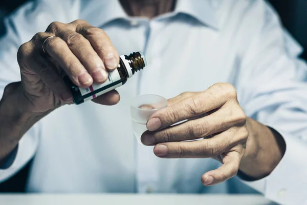 old woman hands close up holding medicine bottle and puts drops