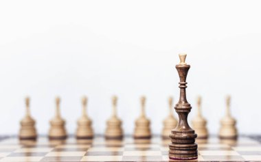 Satranç tahtasında tahta satranç taşları, siyah vezir ve beyaz piyonlar.