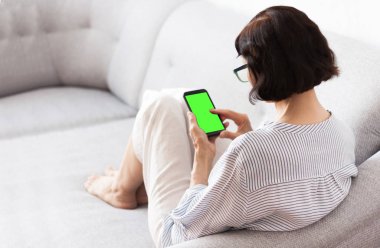 Gri koltukta gözlüklü, orta yaşlı esmer kadın.