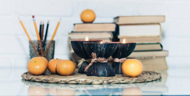 Hindistan cevizi kabuğunda yanan spa aromalı mumlar, hasır üzerinde mandalinalar