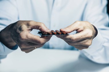 Yaşlı kadın elleri yakın. İlacın su toplamasından bir hap al.,