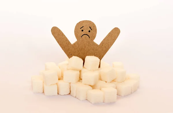Postava muže z lepenky obklopená rafinovanými kostkami cukru na w — Stock fotografie