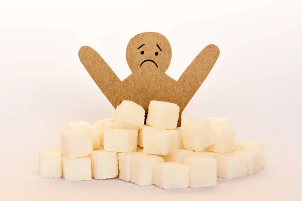 Figure of a cardboard man surrounded by refined sugar cubes on w — Stock Photo, Image