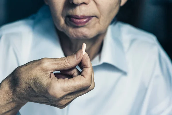 Morena de mediana edad sosteniendo una píldora de la medicina tableta en su — Foto de Stock