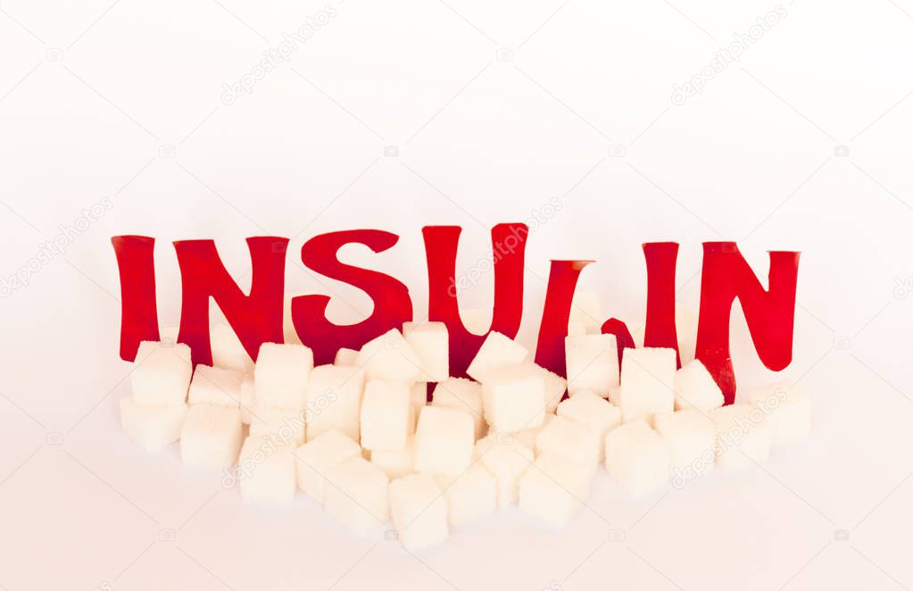 red cardboard insulin word surrounded by refined sugar cubes on 